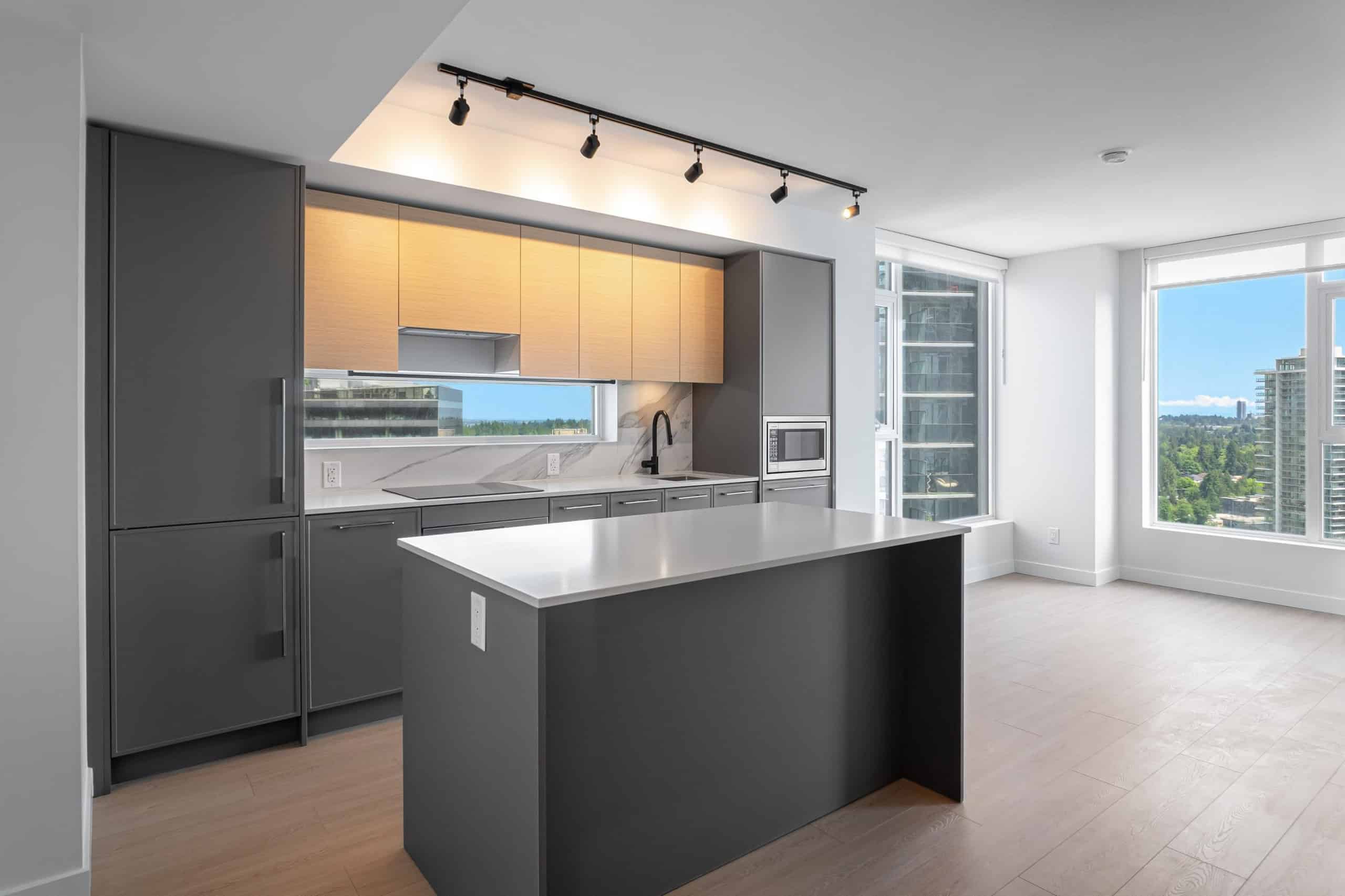 Modern grey and wood kitchen interior with large windows, panoramic city views, minimalist cabinetry, and contemporary appliances – ideal for Vancouver condo living.