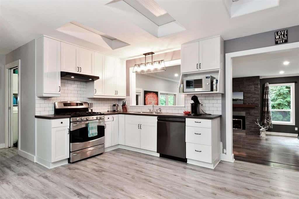 Modern white kitchen with stainless steel appliances, subway tile backsplash, and open layout, ideal for homebuyers seeking contemporary homes in the Orca Realty Inc. portfolio.