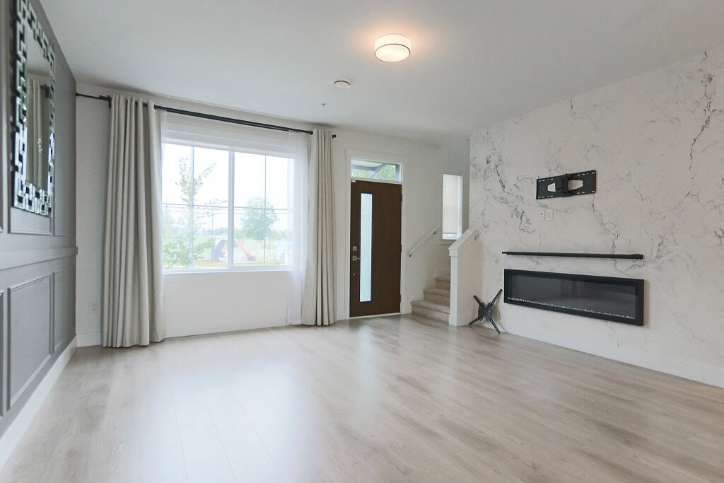 Modern living room with large window, neutral decor, and contemporary fireplace - ideal for homebuyers seeking a stylish and spacious property in Ontario.