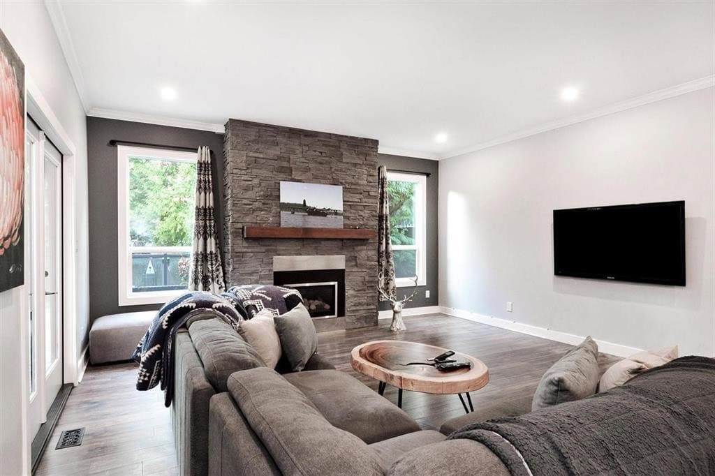 Modern living room with stone fireplace, large windows, grey walls, and comfortable seating, showcasing a welcoming home interior ideal for Vancouver Island real estate.