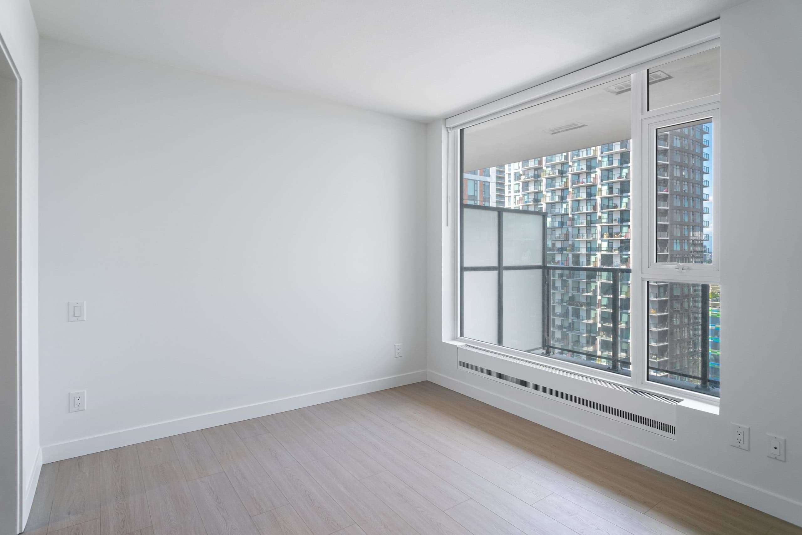 Bright modern condo interior with large windows and city skyline views in Vancouver, British Columbia. Ideal for urban living within a new residential development.