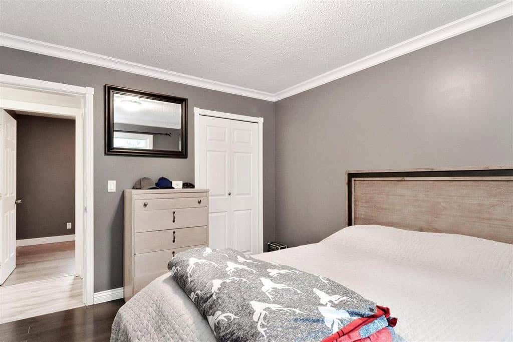 Bright modern bedroom interior with grey walls, white trim, and a cozy bed showcasing Orca Realty Inc. services for Vancouver real estate and property management.