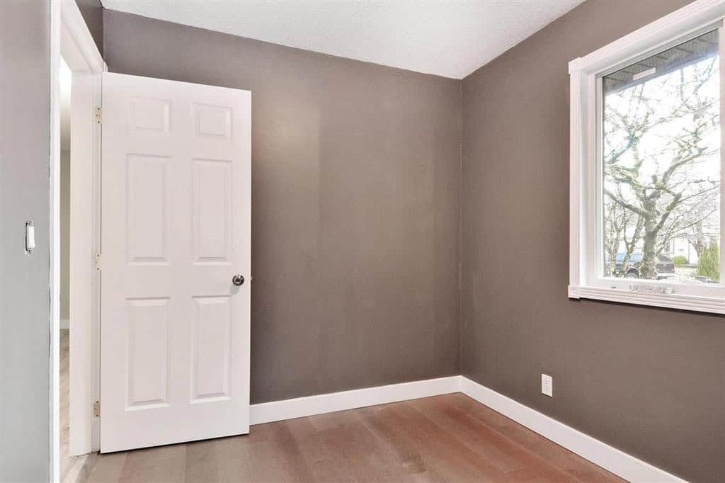 Quiet empty bedroom with a large window and neutral painted walls, ideal for home staging and real estate listings in Vancouver.