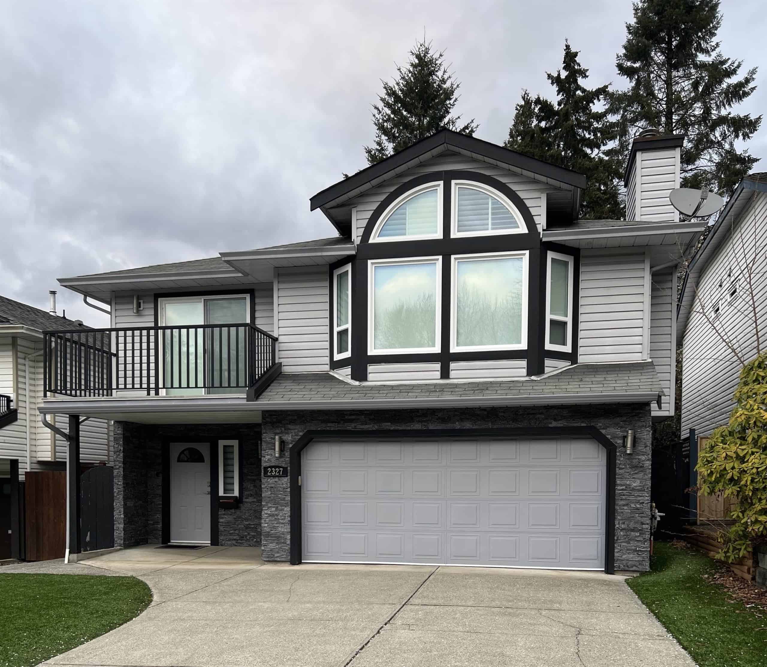 Contemporary modern family home with large bay window, front garage, balcony, grey siding, and landscaped green lawn, available through Orca Realty Inc. in BC, ideal for homebuyers and real estate investors.