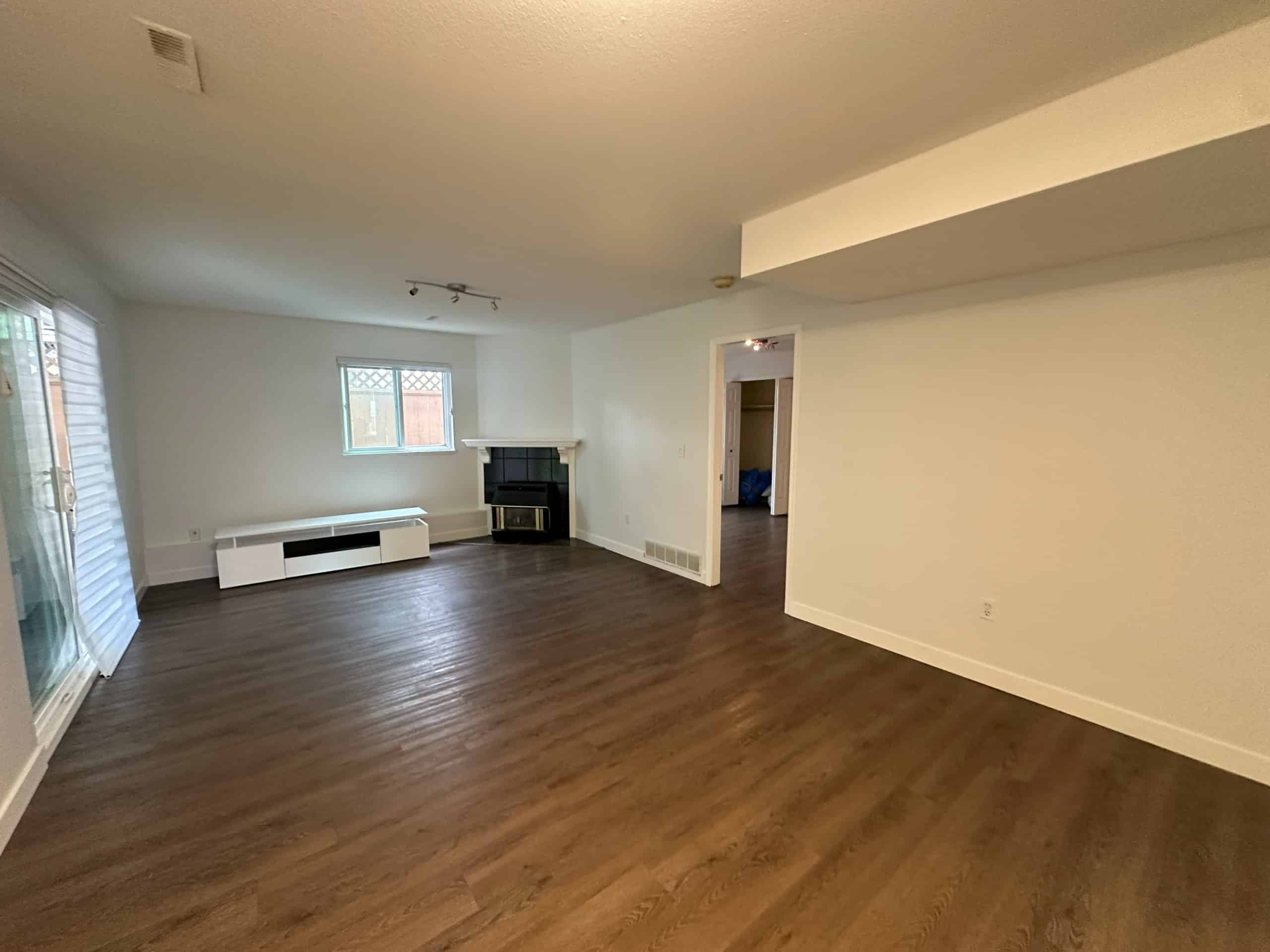 Bright living room with hardwood flooring, large windows, and a cozy fireplace, perfect for family gatherings and entertaining guests in Victoria.