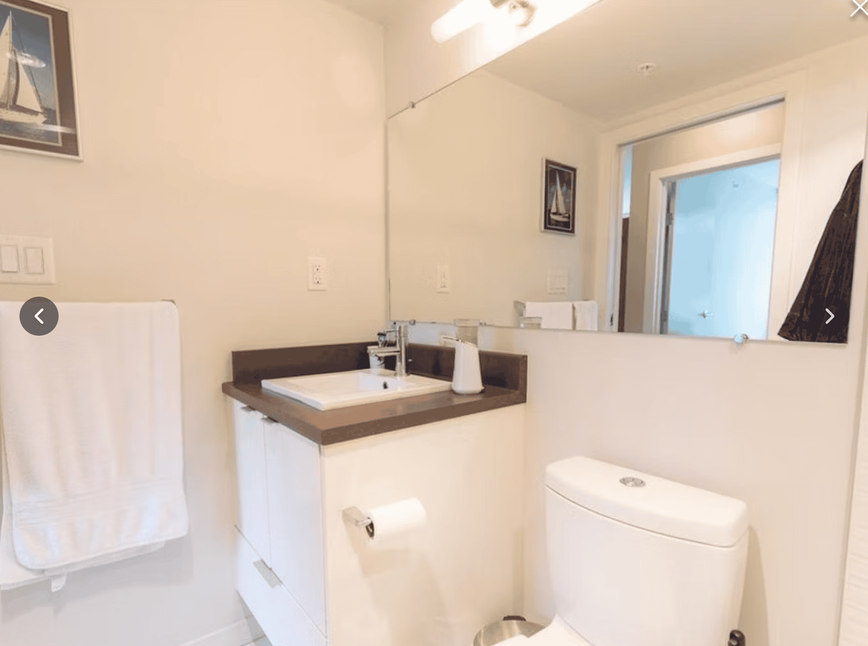 Bathroom with modern sink, toilet, large mirror, and framed artwork, showcasing contemporary interior design and clean, functional amenities. Perfect for real estate listings highlighting home interiors.