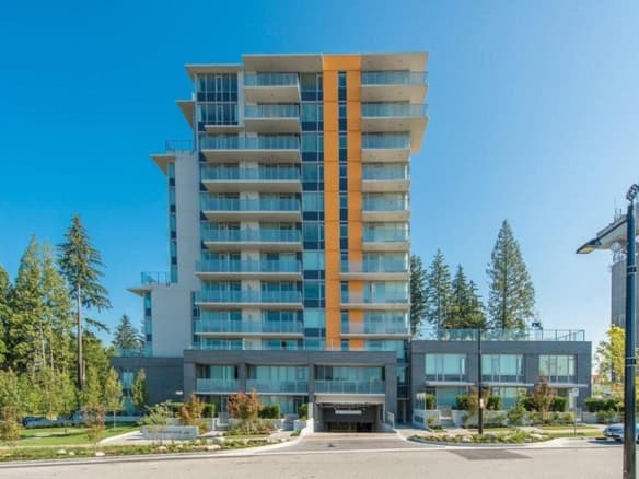 Contemporary multi-story residential building with modern glass balconies and lush landscaping, located in a scenic urban setting, showcasing Orca Realty Inc.'s expertise in Vancouver area real estate.