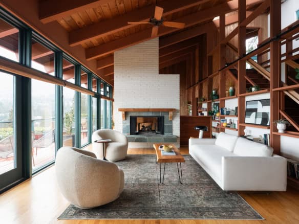 Modern living room with large floor-to-ceiling windows, cozy furniture, and a fireplace, showcasing a stylish, open-concept design ideal for Vancouver real estate.