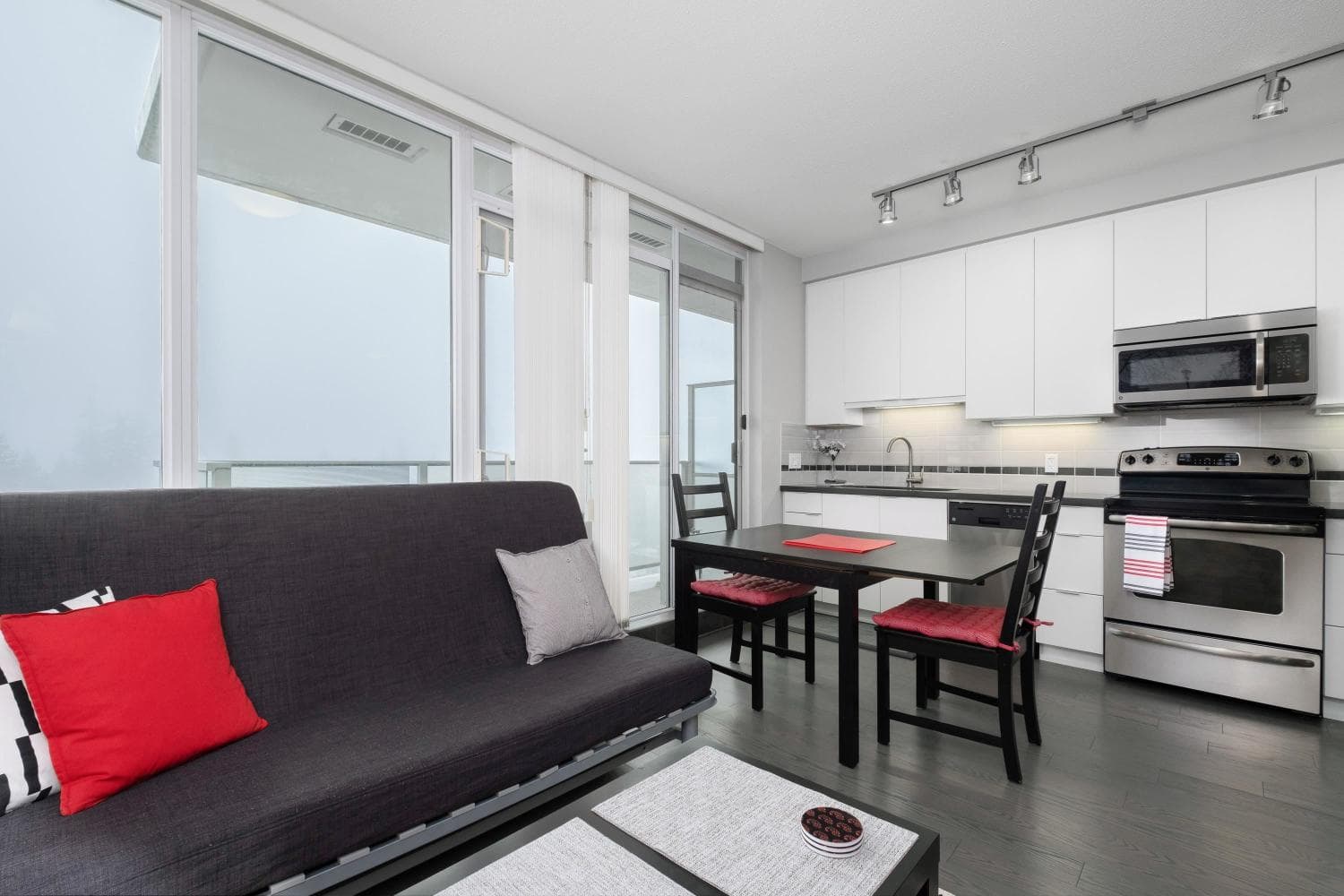 Modern Vancouver-style condo interior with open kitchen, black dining table, and cozy living area, ideal for urban living, investment, or rental property in Vancouver.
