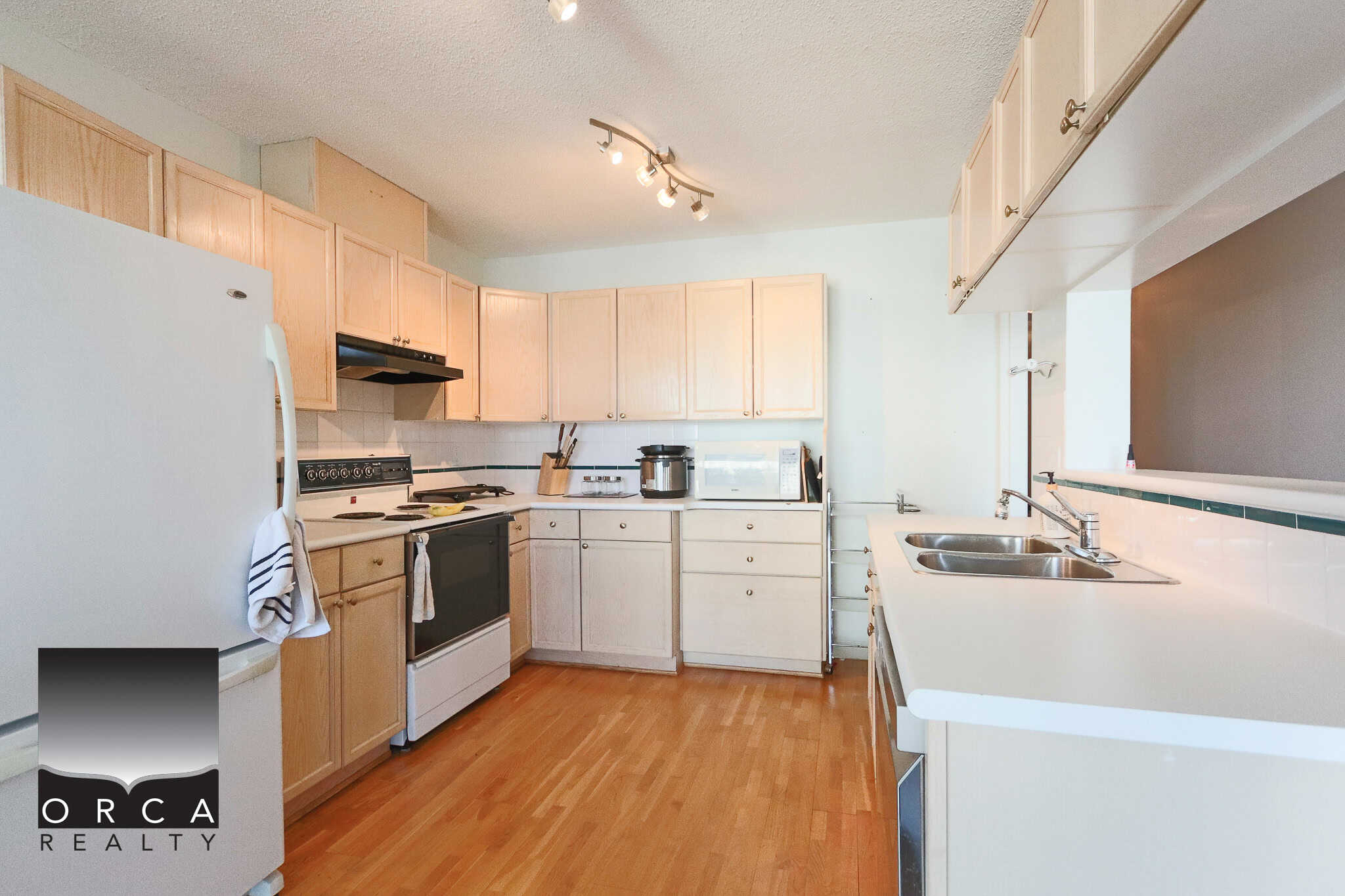 Bright kitchen with white cabinetry, stainless steel sink, and modern appliances, ideal for Vancouver real estate buyers and investors seeking a functional and stylish home kitchen.
