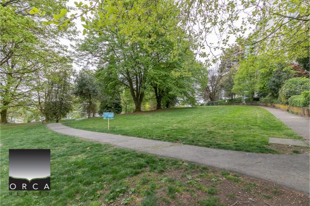 Lush green park with walking paths and mature trees, ideal for outdoor activities and community leisure in Vancouver.