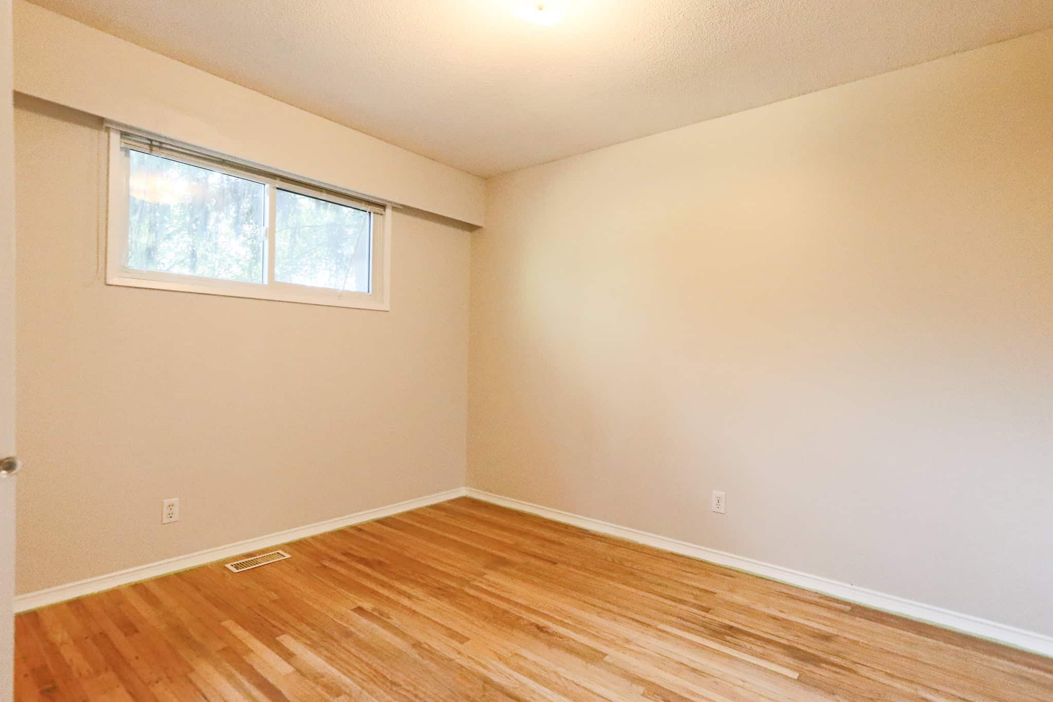 Bright empty bedroom with hardwood flooring and a large window, part of a Vancouver home listed by Orca Realty Inc., ideal for buyers seeking modern real estate options.