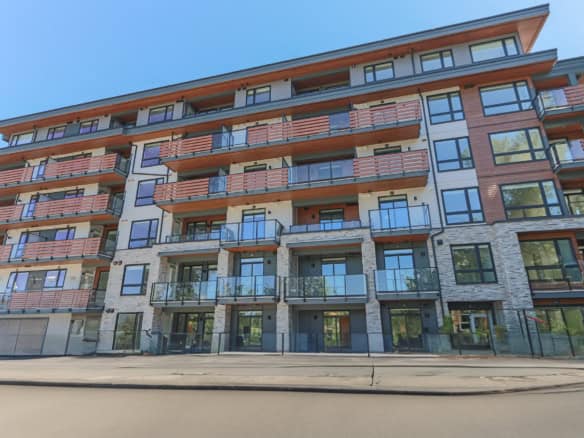 Modern multi-story condo building showcasing contemporary architecture and large glass balconies in a desirable neighbourhood. Perfect for homebuyers and investors in Vancouver real estate.