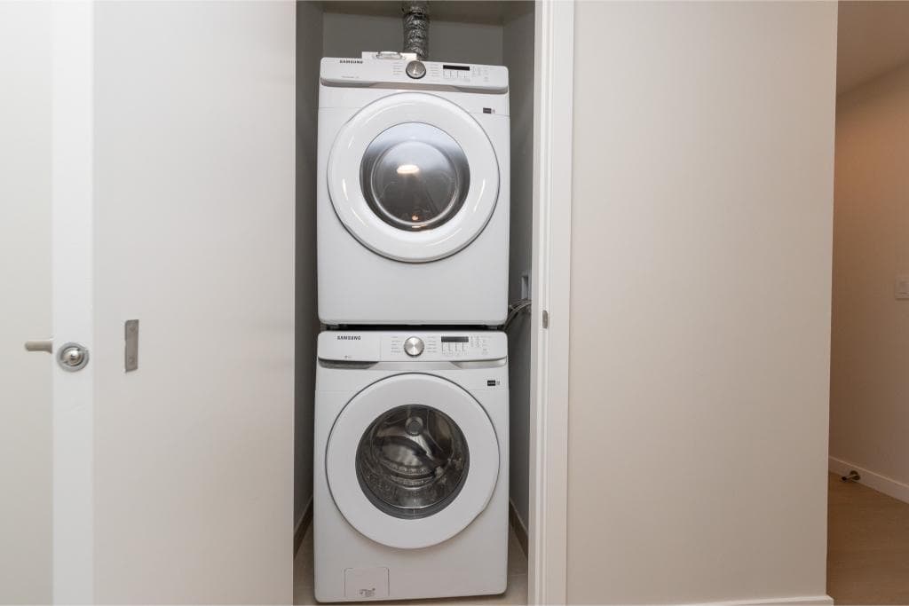 Stacked front-load washing machine and dryer in a laundry closet at Orca Realty Inc., Vancouver real estate, modern home amenities, laundry appliances, clean and functional laundry space.