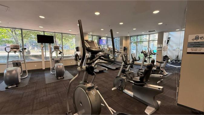 Elliptical cardio machines and exercise bikes in a modern, well-lit gym at Orca Realty Inc. offering clients fitness amenities as part of their property services in Victoria BC.