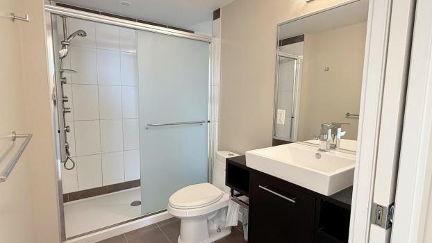 Modern bathroom with walk-in shower, white tile walls, and contemporary vanity, showcasing upscale interior design and sleek fixtures for Vancouver real estate.