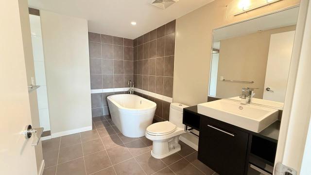 Modern bathroom with freestanding bathtub, stylish black vanity, and contemporary fixtures in a bright, spacious design. Perfect for luxury condo or home decor in Vancouver.
