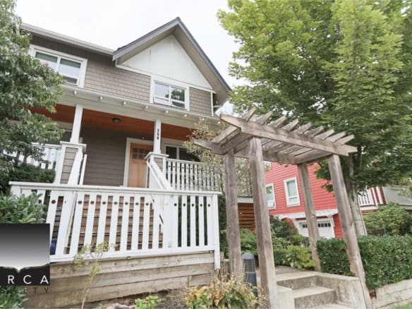 Charming two-story home with a front porch, surrounded by lush greenery and mature trees in a desirable neighbourhood. Features a white picket fence, modern design, and a cozy outdoor seating area.