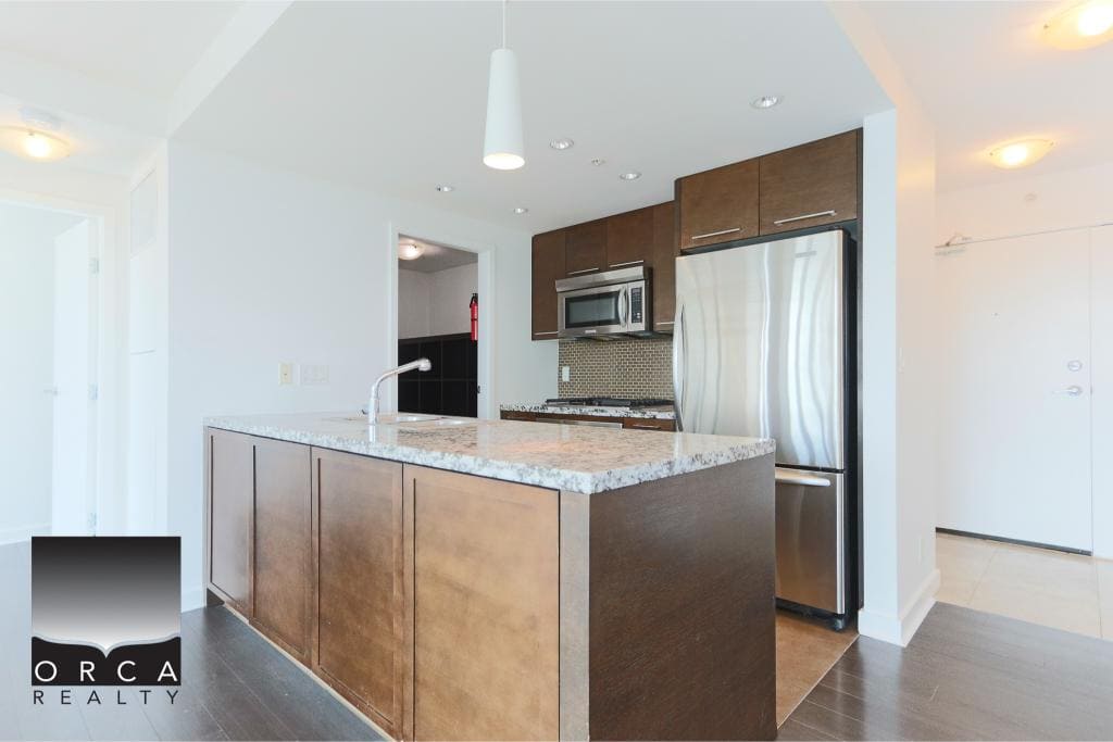 Contemporary kitchen with stainless steel appliances and granite countertops, ideal for modern Vancouver Island homes. Perfect for buyers seeking stylish, functional, and high-quality real estate.