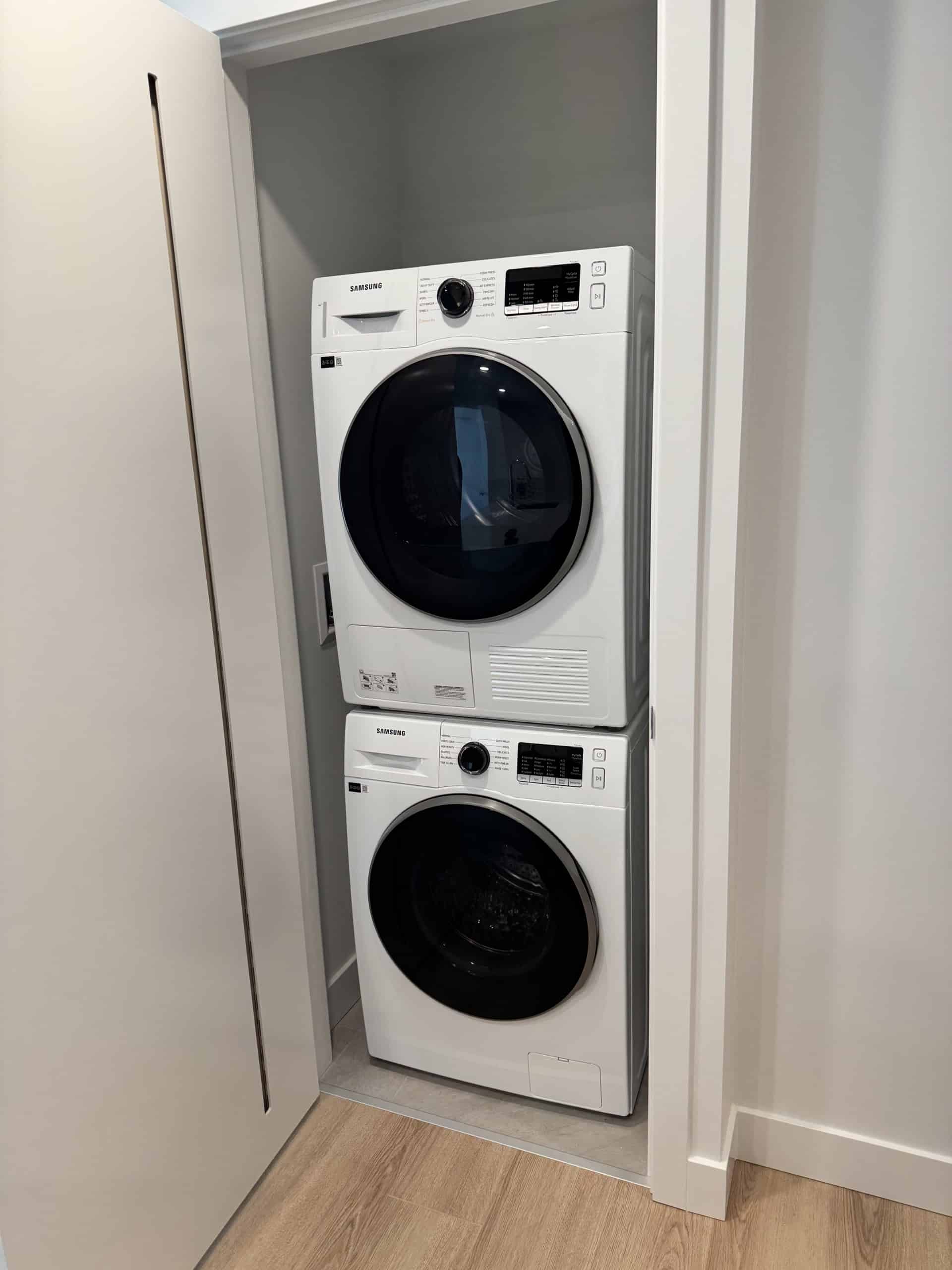 Front-loading washer and dryer unit in a modern laundry nook at Orca Realty Inc., Vancouver real estate, showing stylish appliances for a contemporary home.