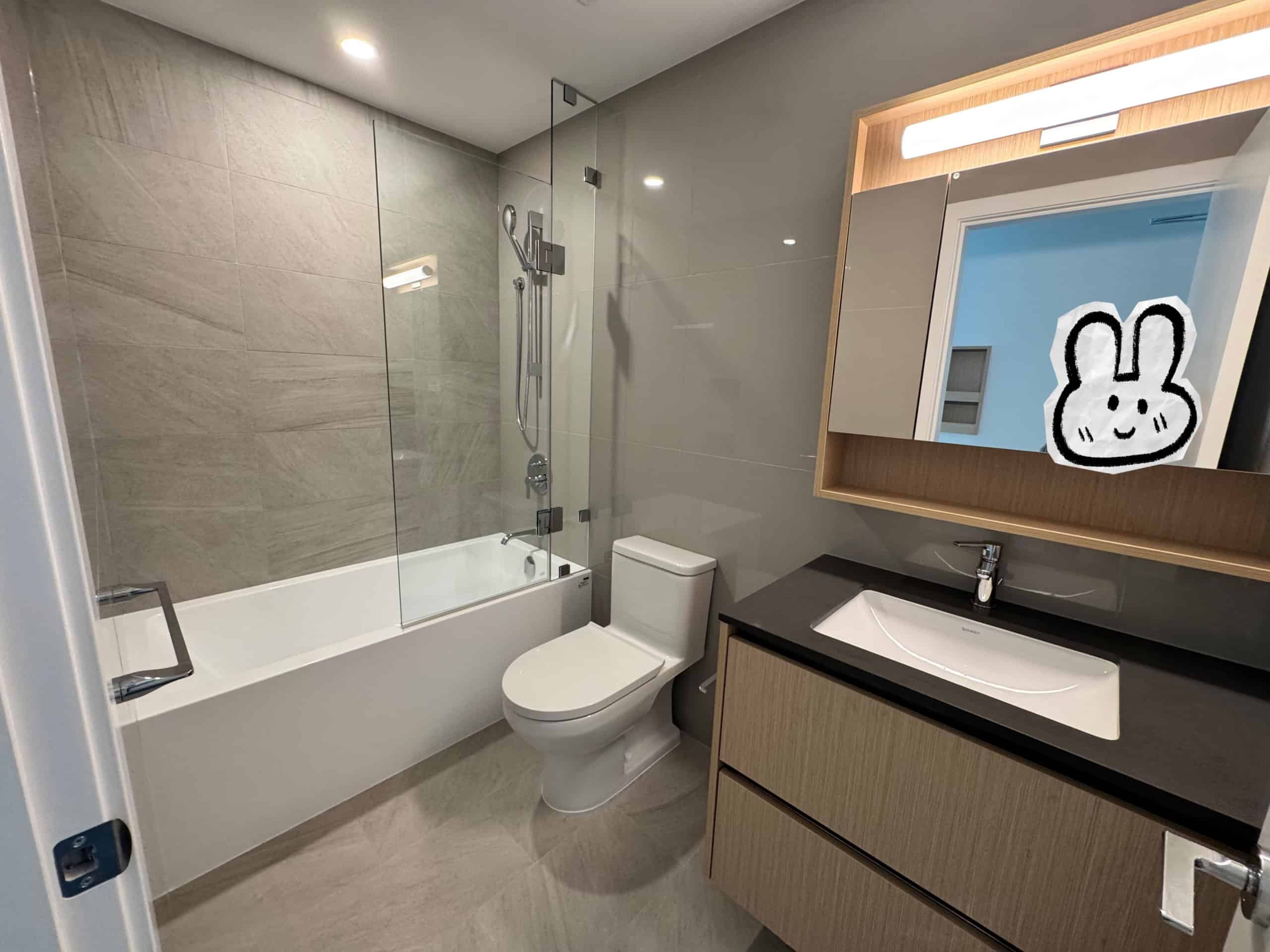 Modern bathroom with a sleek design, featuring a glass-enclosed shower, white bathtub, contemporary sink with wooden cabinetry, and a large mirror illuminated by LED lighting.
