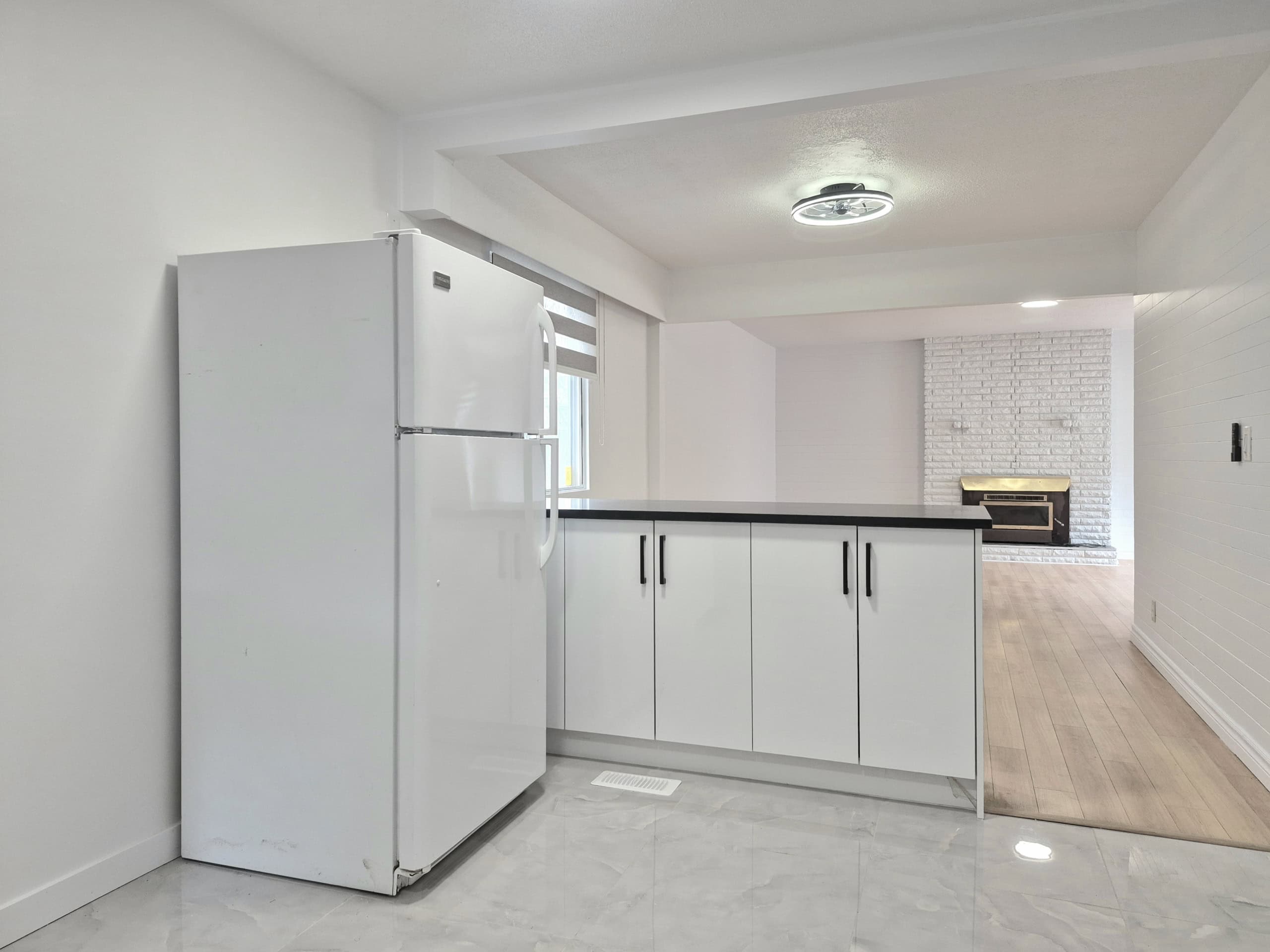 1000050311 Stainless steel refrigerator in a modern kitchen, featuring white cabinets and light wood flooring, ideal for contemporary home living.