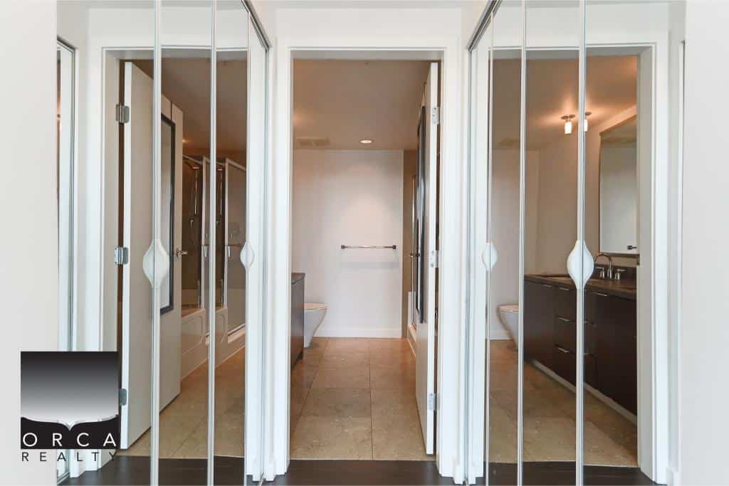 Bright modern bathroom with glass closet doors, dual sinks, and spacious design, perfect for luxury home buyers seeking stylish and functional real estate in BC.