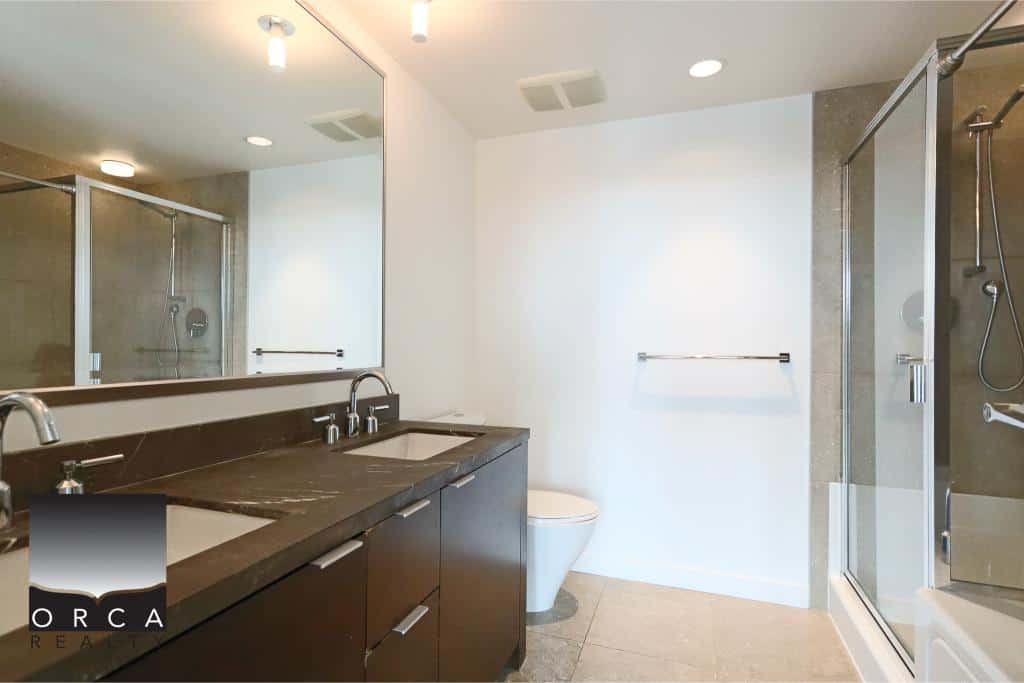 Modern bathroom with double vanity, glass shower enclosure, and contemporary fixtures showcasing Orca Realty Inc. services in Vancouver real estate.