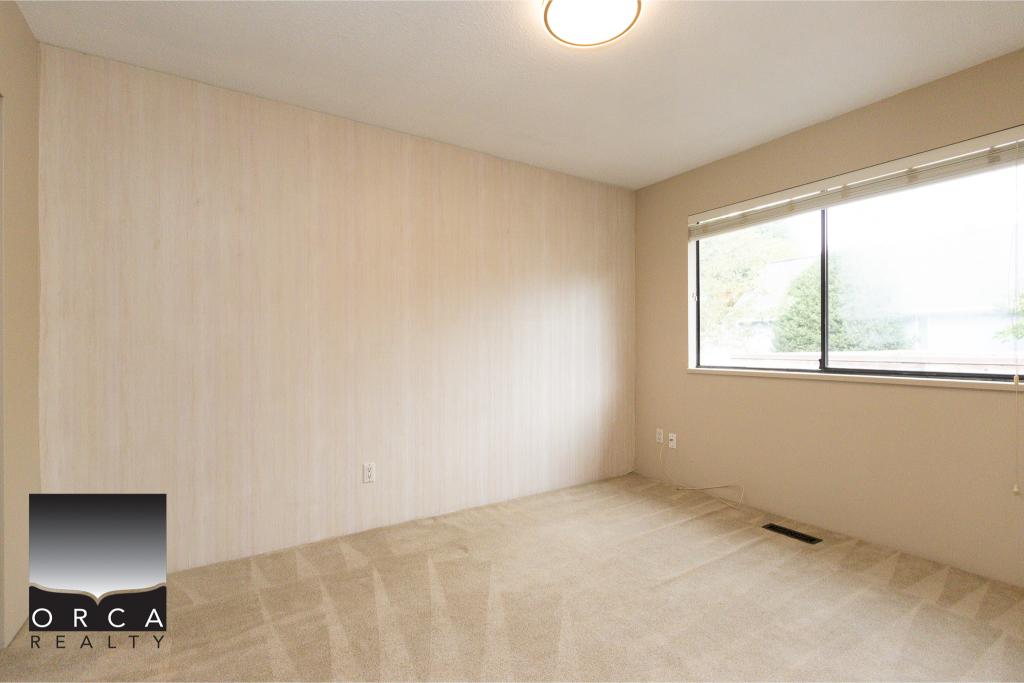 Bright, empty in-ceiling room with large window, beige carpet, and neutral walls, ideal for Vancouver Island home or condo; perfect for buyers seeking modern, move-in ready real estate options.