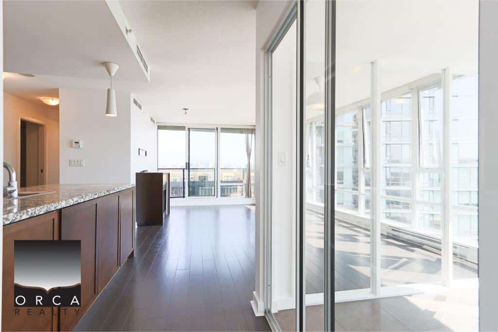 Bright modern condo interior with large windows and city views, featuring an open living space and balcony access, ideal for urban living in Vancouver.