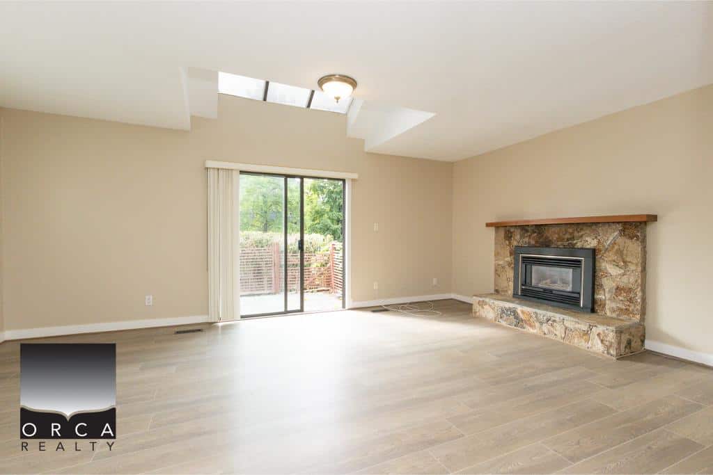Spacious living room with fireplace and sliding glass door leading to backyard, ideal for real estate showcasing and home sales in Victoria, BC.