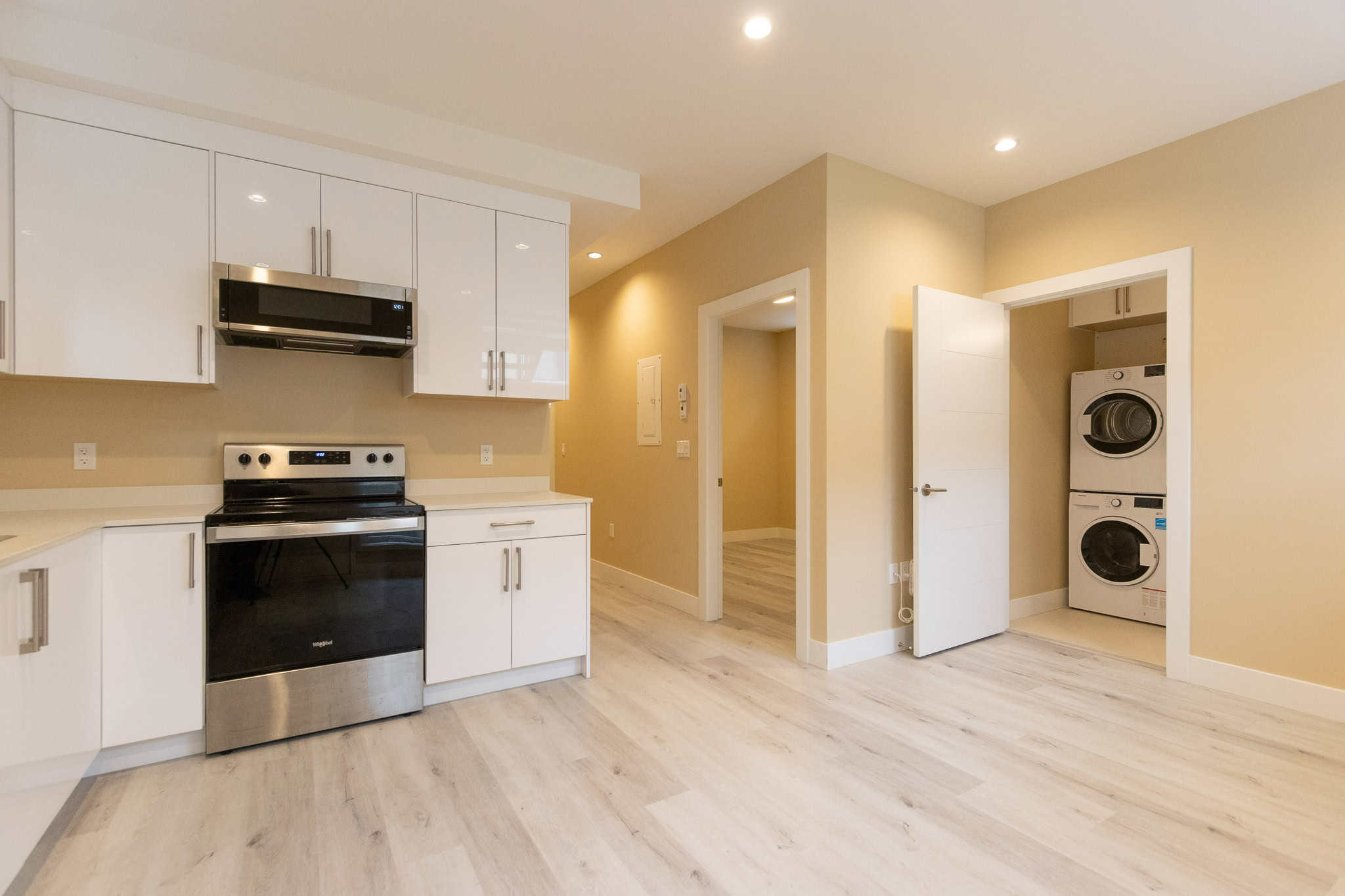 2 Modern kitchen with white cabinetry, integrated appliances, and light wood flooring at Orca Realty Inc. Vancouver Island real estate.