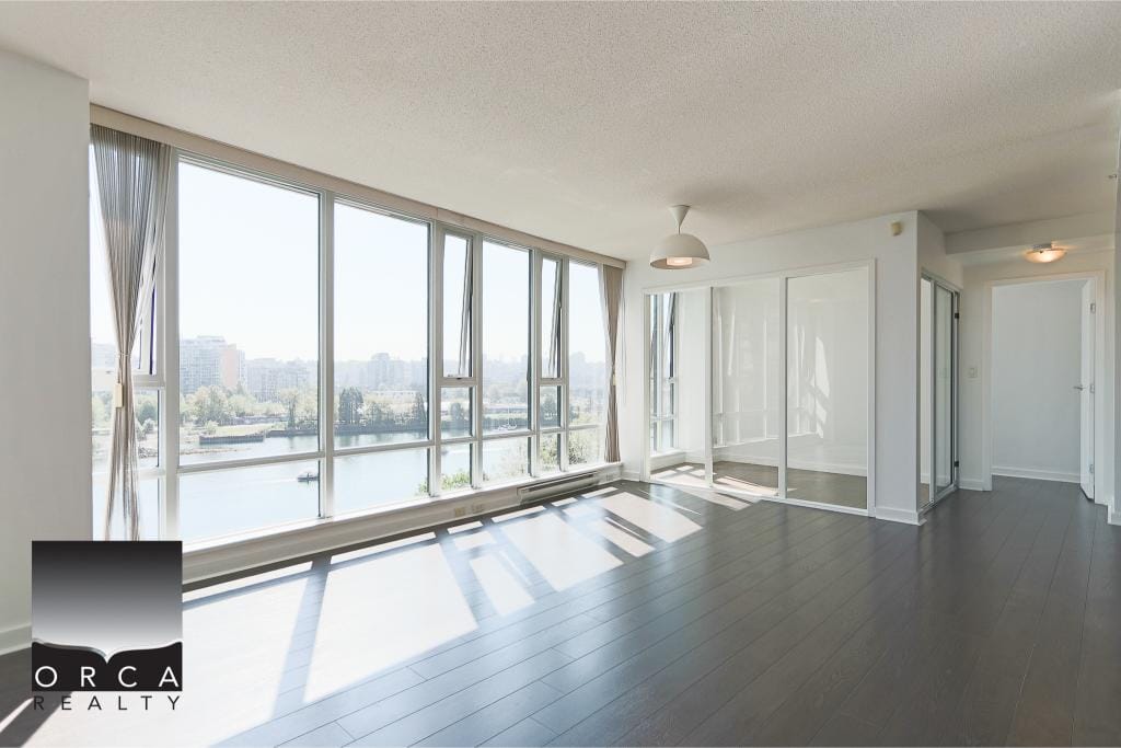 Bright waterfront condo living space with large floor-to-ceiling windows, showcasing scenic city and river views, modern interior design, ideal for Vancouver real estate buyers.