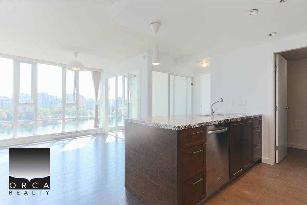 Luxury waterfront condo interior with large windows offering scenic views, modern kitchen with granite countertops, and open living space. Perfect for Vancouver real estate buyers.
