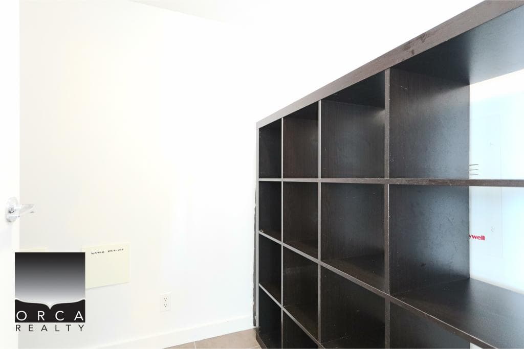 Empty black bookshelf in modern office space, clean white walls, and minimalist decor, ideal for real estate and commercial property listings on Orca Realty Inc. website.