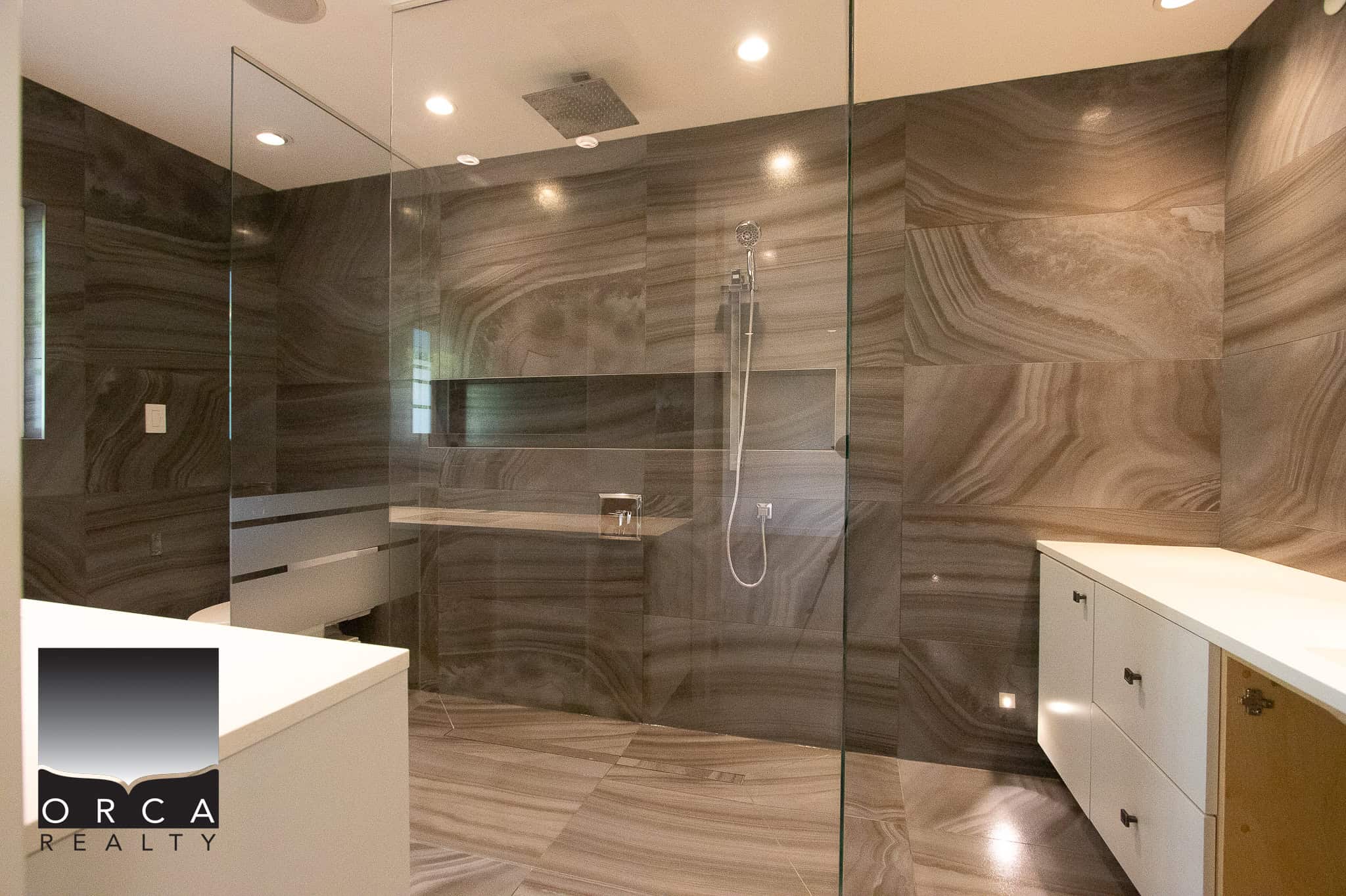 Elegantly designed modern bathroom with dark marble walls and spacious glass shower, floating vanity, and sleek fixtures, perfect for luxury living.