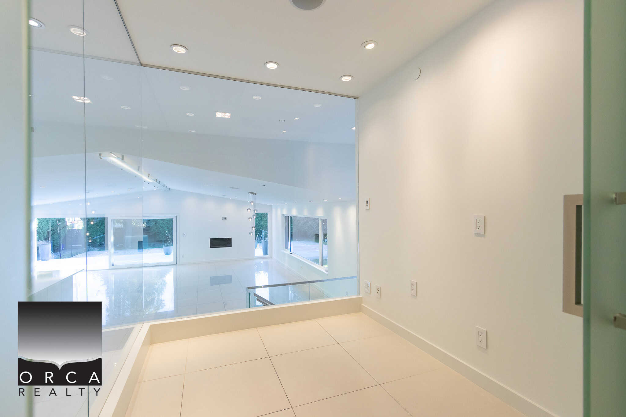 Modern interior view of a luxury Vancouver home with large glass windows, sleek white walls, and contemporary lighting, illustrating Inverness property listings by Orca Realty Inc.