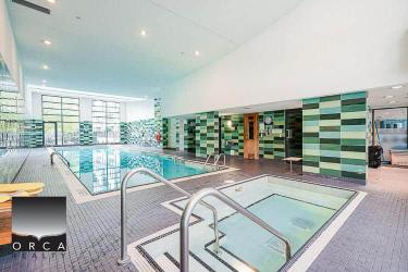 Indoor swimming pool and hot tub at Orca Realty Inc. office, modern amenities, sleek design, perfect for relaxation and fitness, professional real estate services in a luxurious setting.