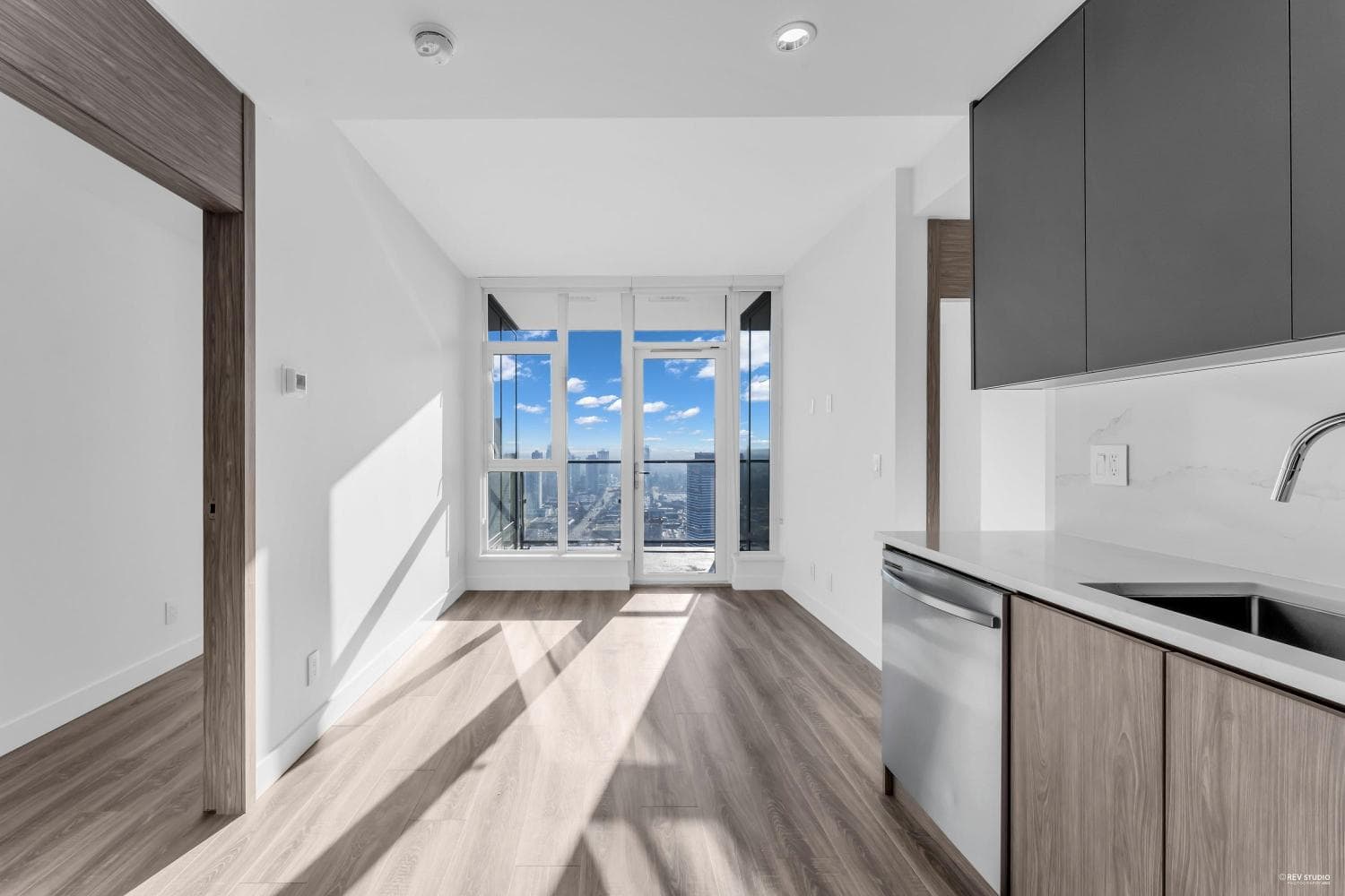 Modern high-rise condo living with floor-to-ceiling windows offering panoramic city views, open concept kitchen, and contemporary finishes in downtown Vancouver.