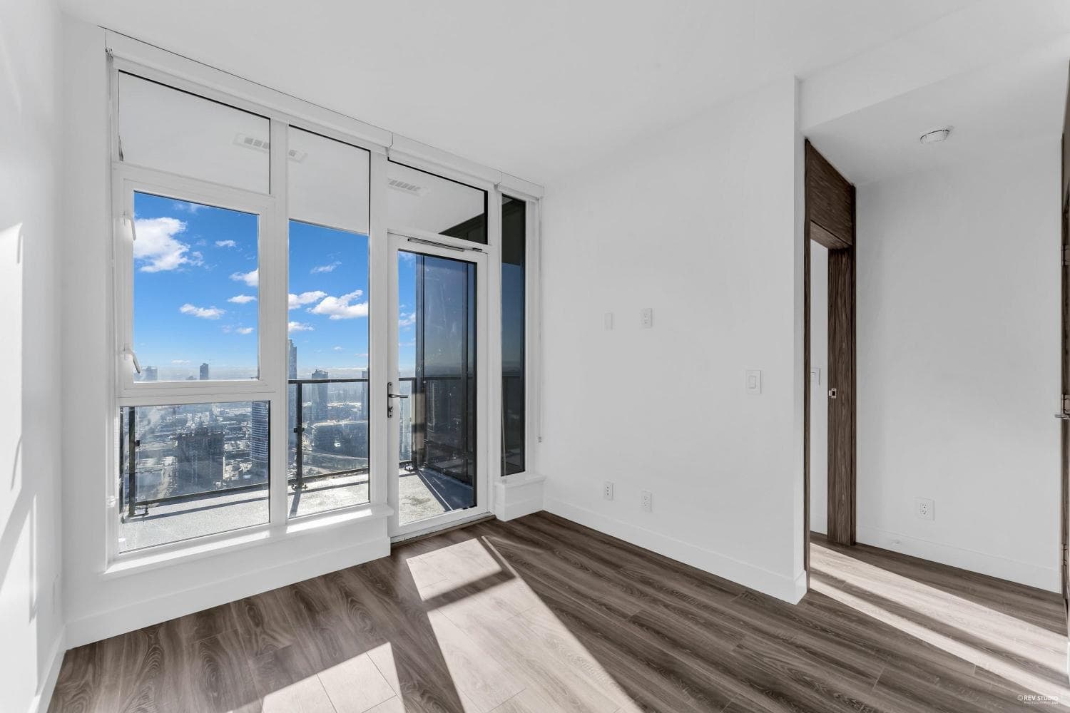 Stunning interior view of a modern high-rise condo with floor-to-ceiling windows, offering panoramic city skyline views, hardwood flooring, and natural light, by Orca Realty Inc.