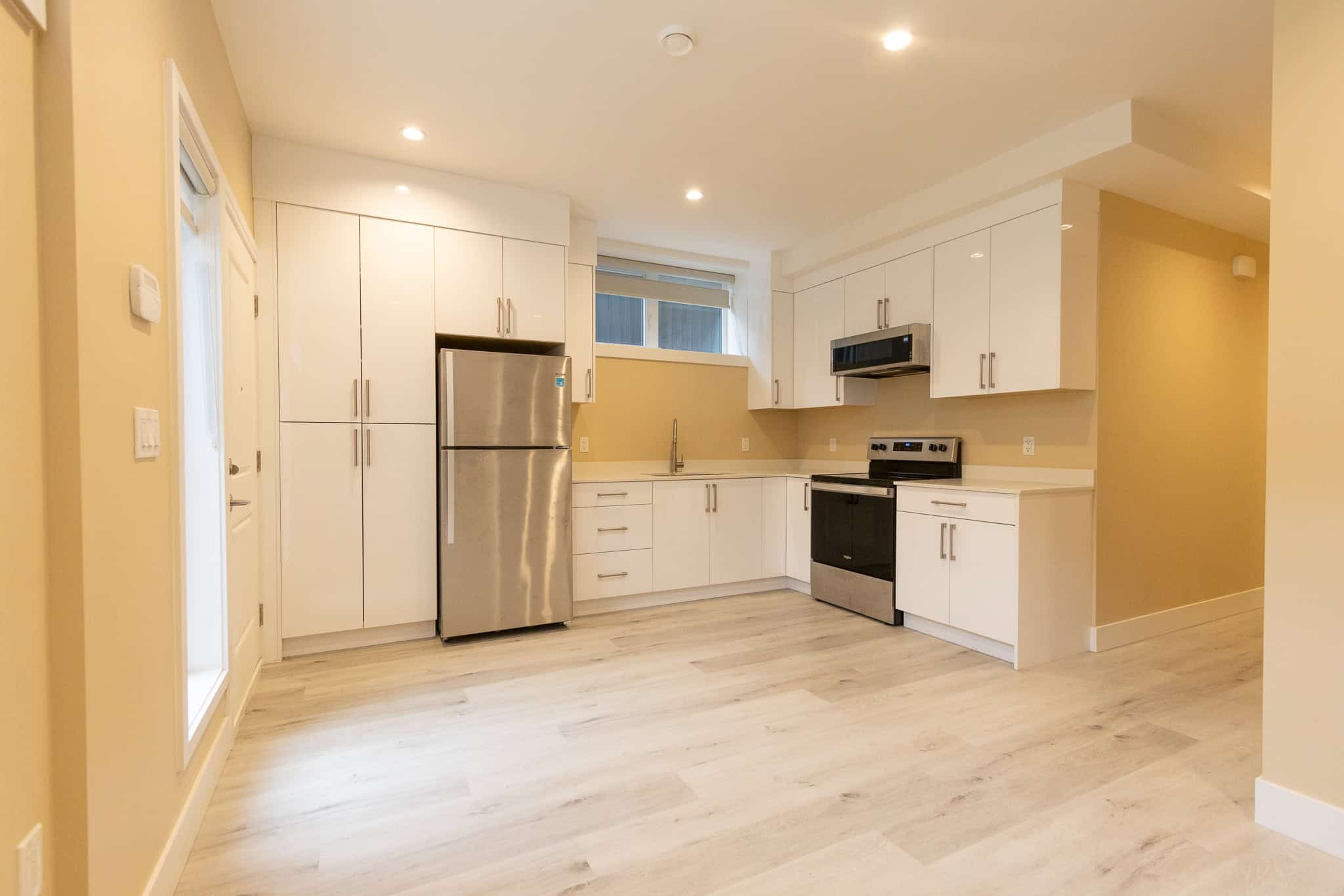 3 Modern kitchen with white cabinetry, stainless steel appliances, and light wood flooring in a property listed by Orca Realty Inc.