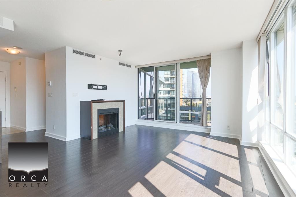 Spacious Vancouver high-rise condo living room with large windows, city views, modern design, and a fireplace, available through Orca Realty Inc.