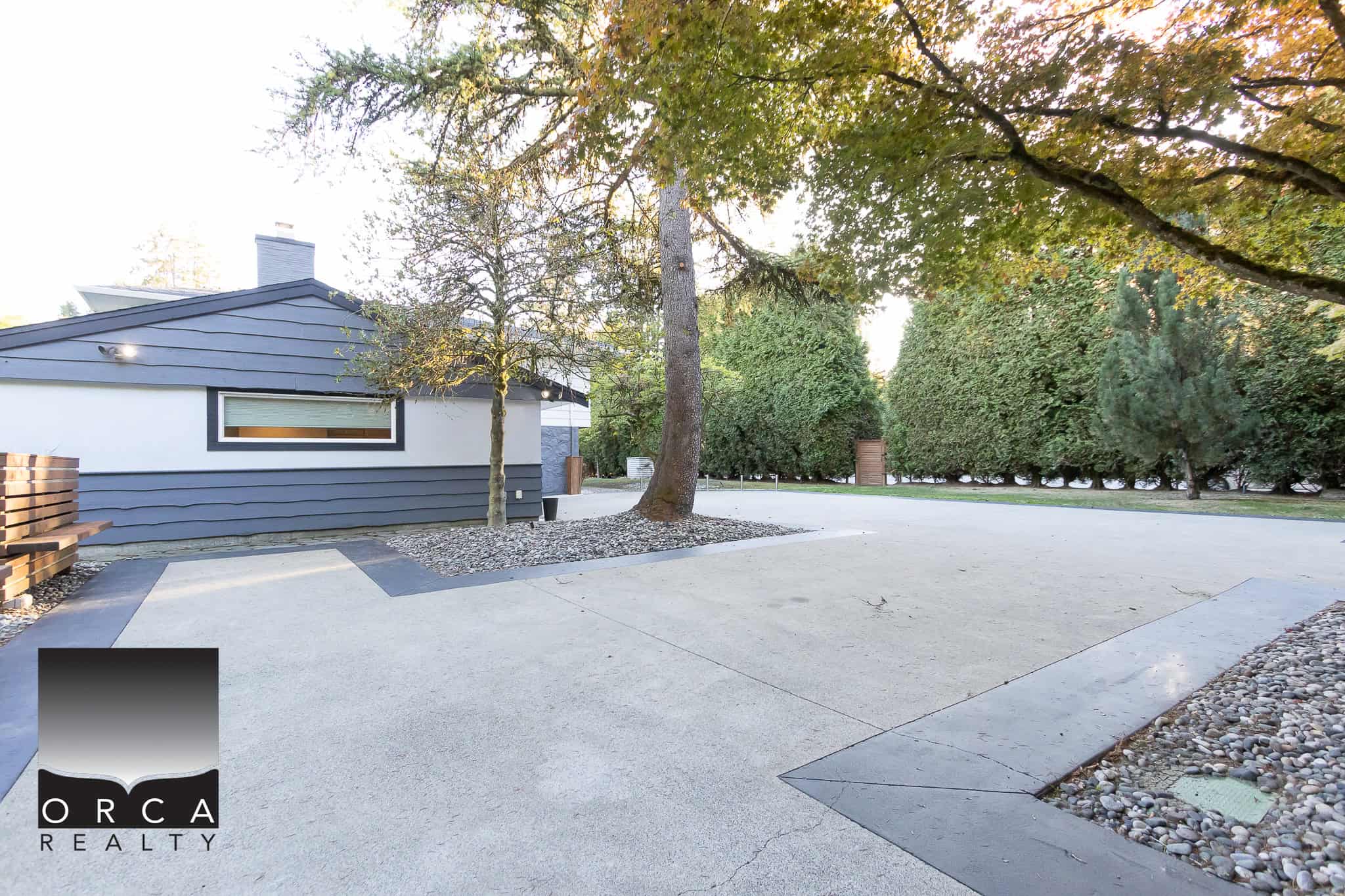 Modern residential property with landscaped driveway and lush trees, showcasing contemporary architecture in a serene neighbourhood.