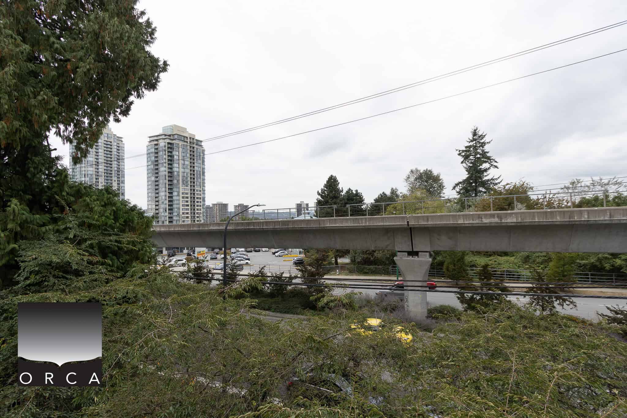Modern Vancouver cityscape with high-rise buildings, green trees, and an overpass, showcasing prime real estate opportunities and urban living options.