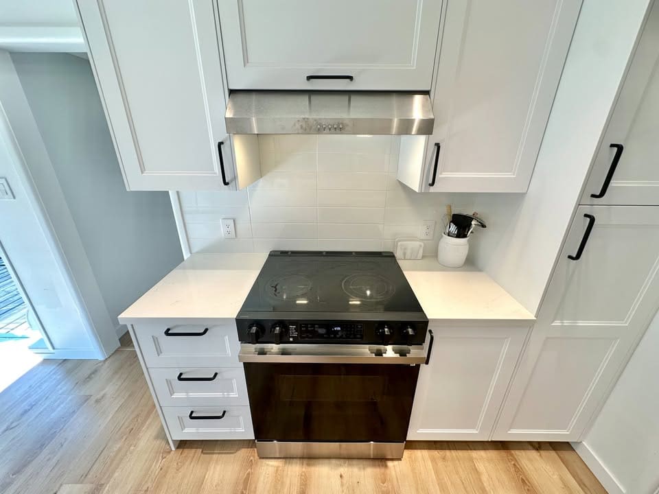 Modern kitchen with white cabinetry, black handles, stainless steel oven, and minimalist design, perfect for Vancouver real estate listings and showcasing contemporary home interiors.