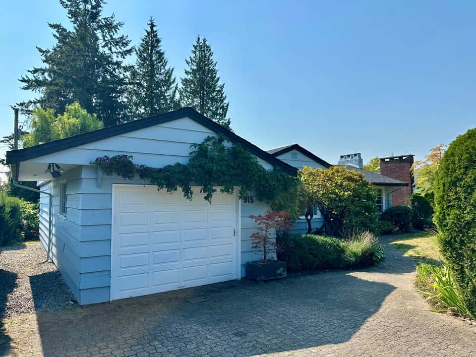 Detached single-family home with a white garage, lush landscaping, and a scenic driveway; ideal for buyers seeking homes in picturesque neighbourhoods.