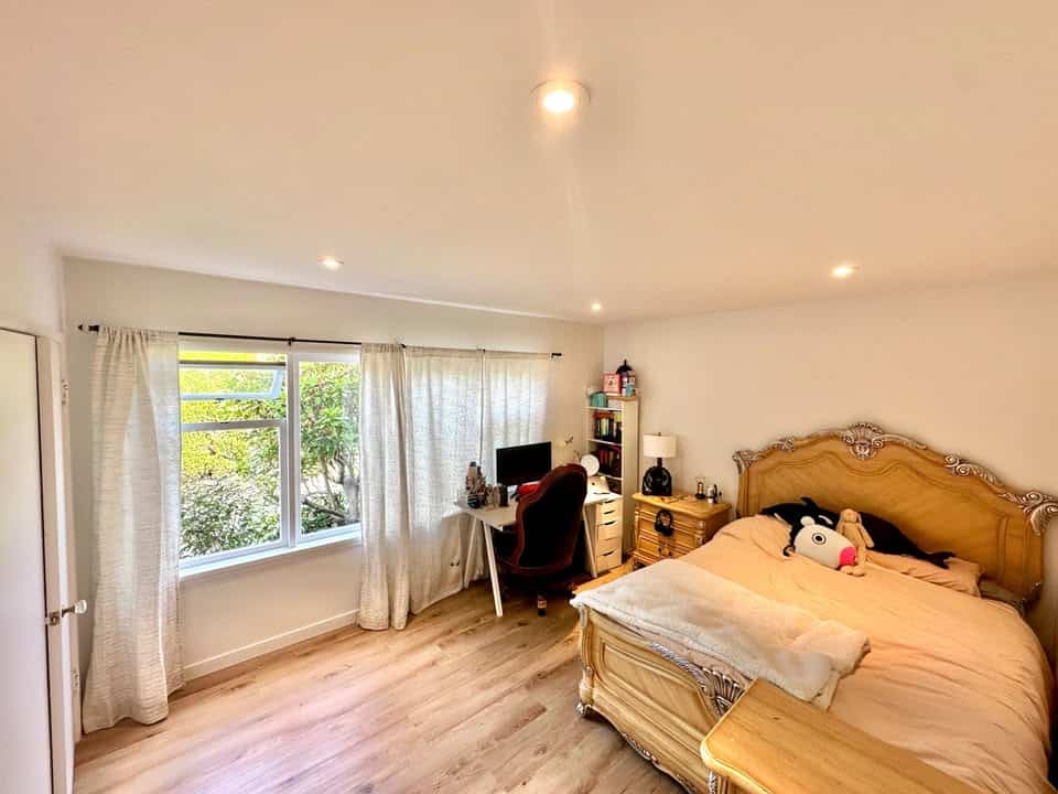 Spacious bedroom with large window, home office setup, and elegant furniture in a Vancouver property listed by Orca Realty Inc.