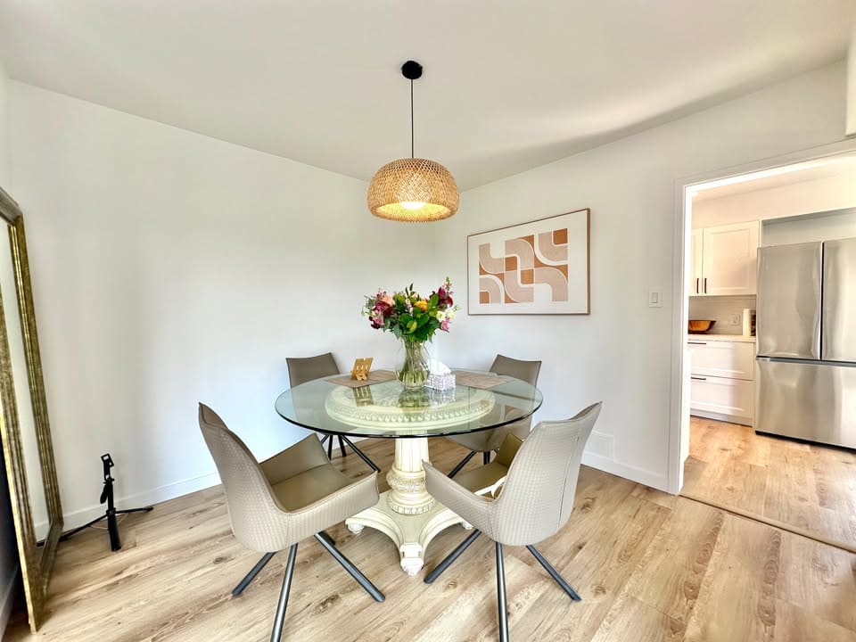 Modern dining room with round glass table, beige chairs, and contemporary wall art, featuring a cozy and stylish atmosphere perfect for family meals or entertaining guests in a Vancouver home.