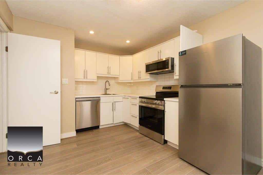 Modern fully equipped kitchen with stainless steel appliances and white cabinetry, available through Orca Realty Inc., ideal for Vancouver Island real estate buyers.