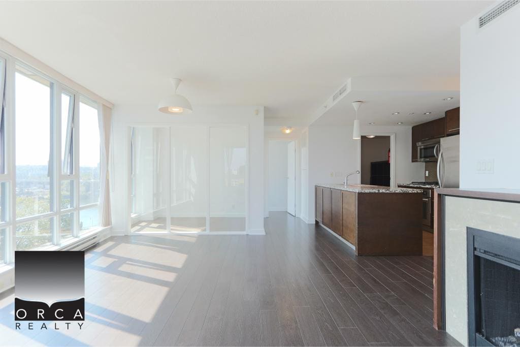 Bright, modern open-concept living room and kitchen in Vancouver apartment, featuring large windows with city views, hardwood flooring, stainless steel appliances, and stylish décor, perfect for real estate listings.